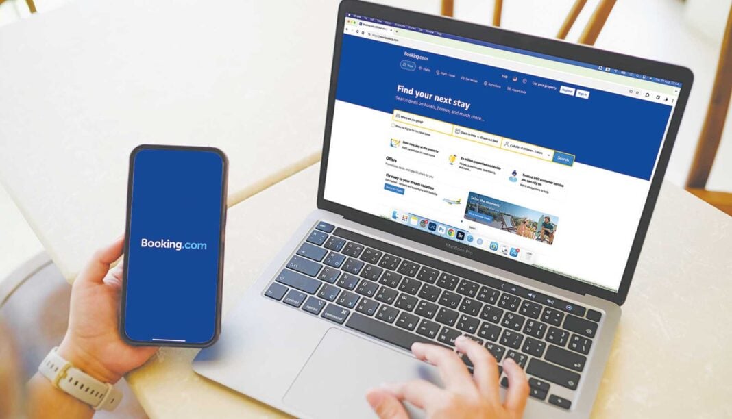 Ένας άντρας κοιτάει την εφαρμογή booking.com μέσα από ένα λάπτοπ και από το κινητό Ένας άντρας κοιτάει την εφαρμογή booking.com μέσα από ένα λάπτοπ και από το κινητό