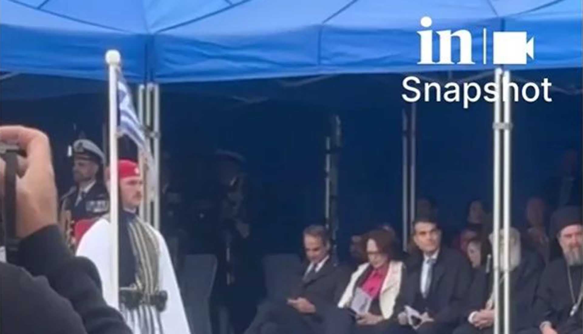 Ο Κυριάκος Μητσοτάκης κοιτάει το κινητό του κατά τη διάρκεια της παρέλασης