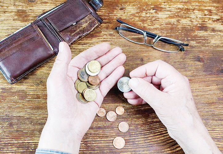 Άνθρωπος έχει βγάλει τα κέρματα από το πορτοφόλι του και τα μετράει στη χούφτα Άνθρωπος έχει βγάλει τα κέρματα από το πορτοφόλι του και τα μετράει στη χούφτα